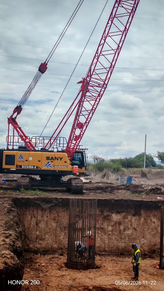 Equipo de perforación y grúa de celosía trabajando en una excavación para cimentación