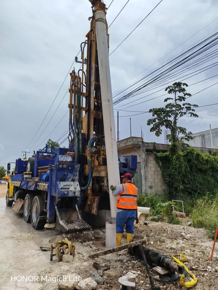 Equipo de perforación montado en camión junto a un pilote de concreto